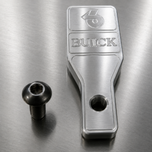 Buick metal part with screw on table.