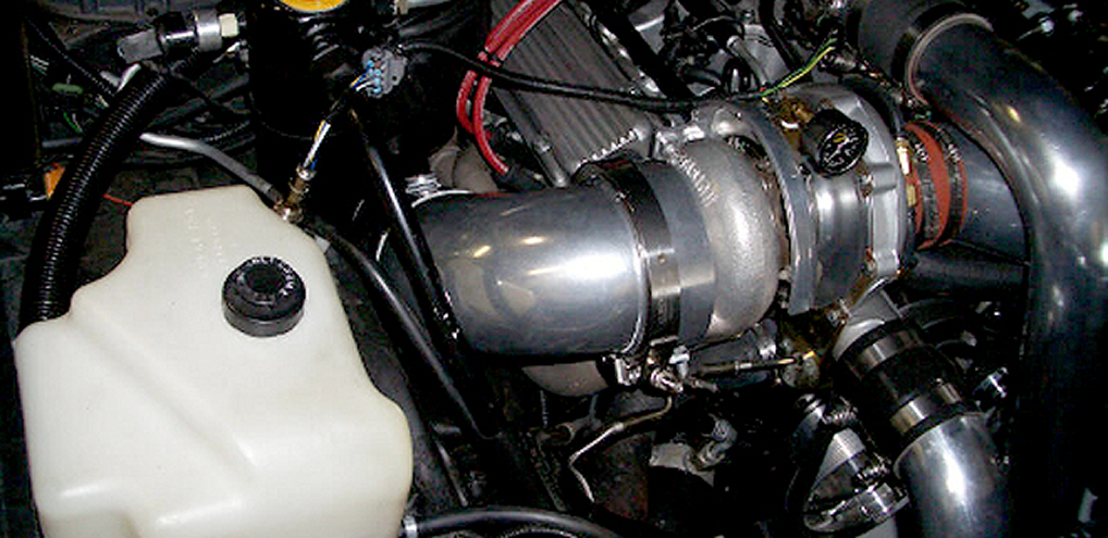 Performance car engine with exposed turbo