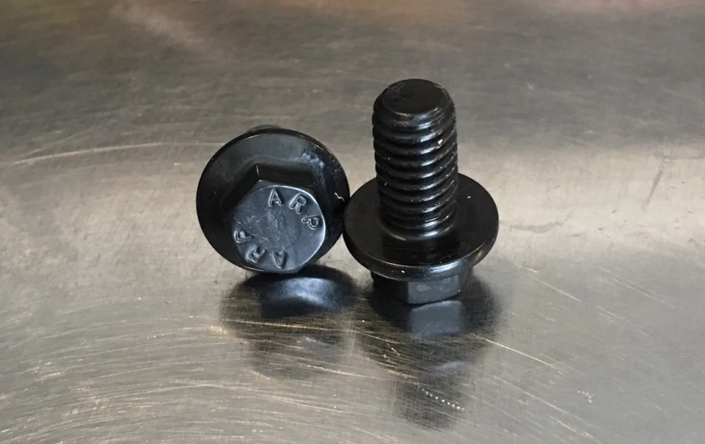 Black ARP bolts on metal surface